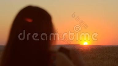 女孩带着手机在日落黄昏的风景图片在手机上日落美丽。